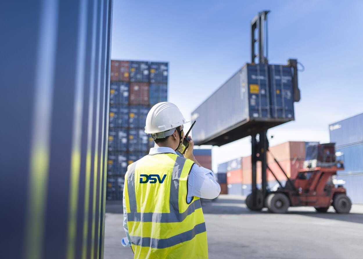 DSV medarbeider snakker i walkie talkie mens en sjøcontainer blir løftet av truck